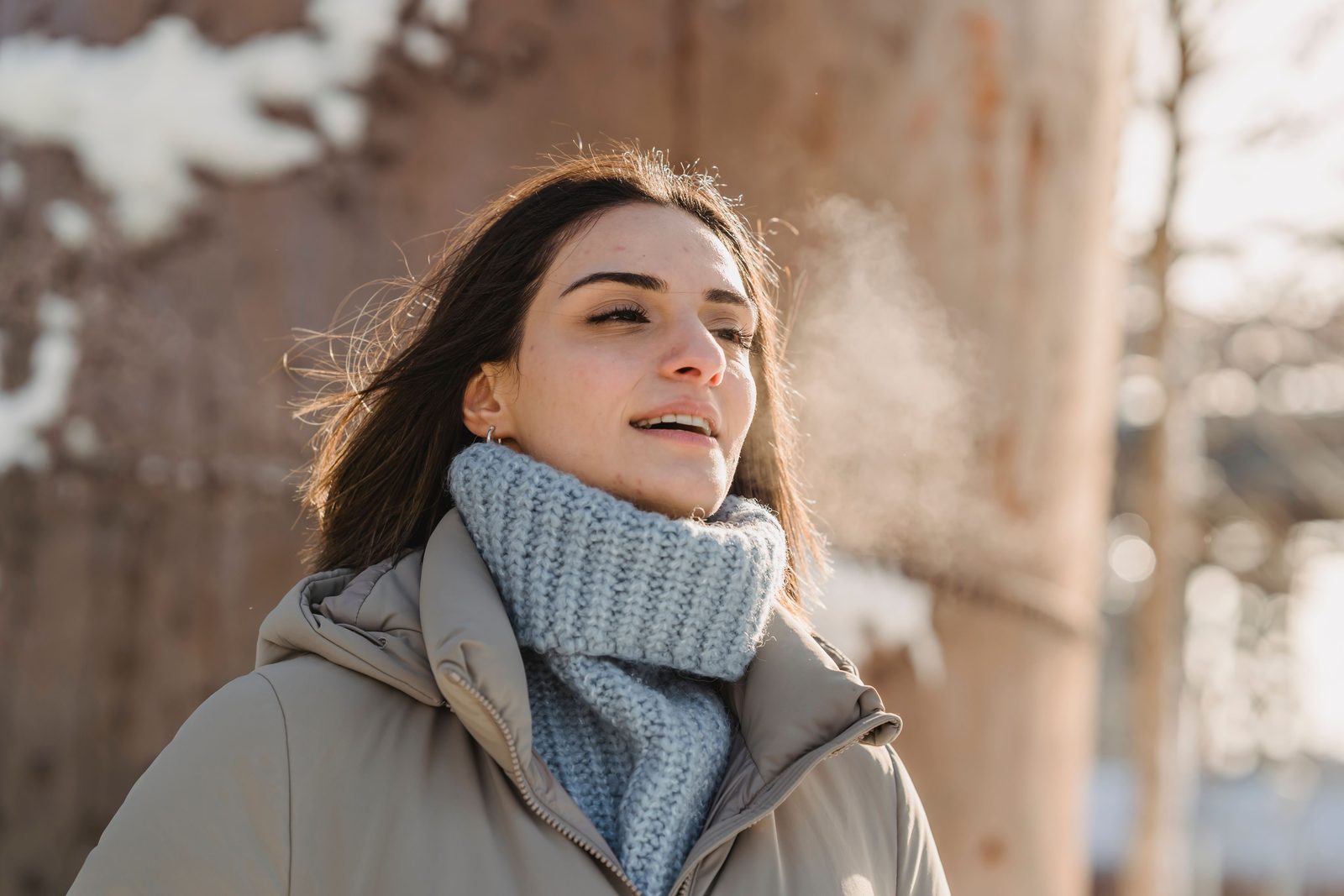 Woman in a winter coat with her breath visible in the cold air